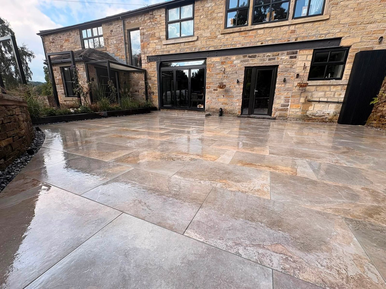Large travertine stone patio installed by DB Landscapes Ltd, landscape gardeners in Stockport